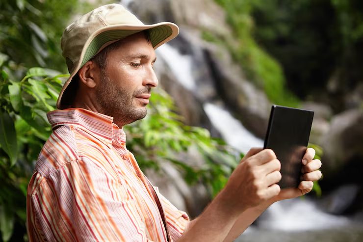 A researcher checking a tablet in the field, representing the field-researcher end of EcoLink's range of users