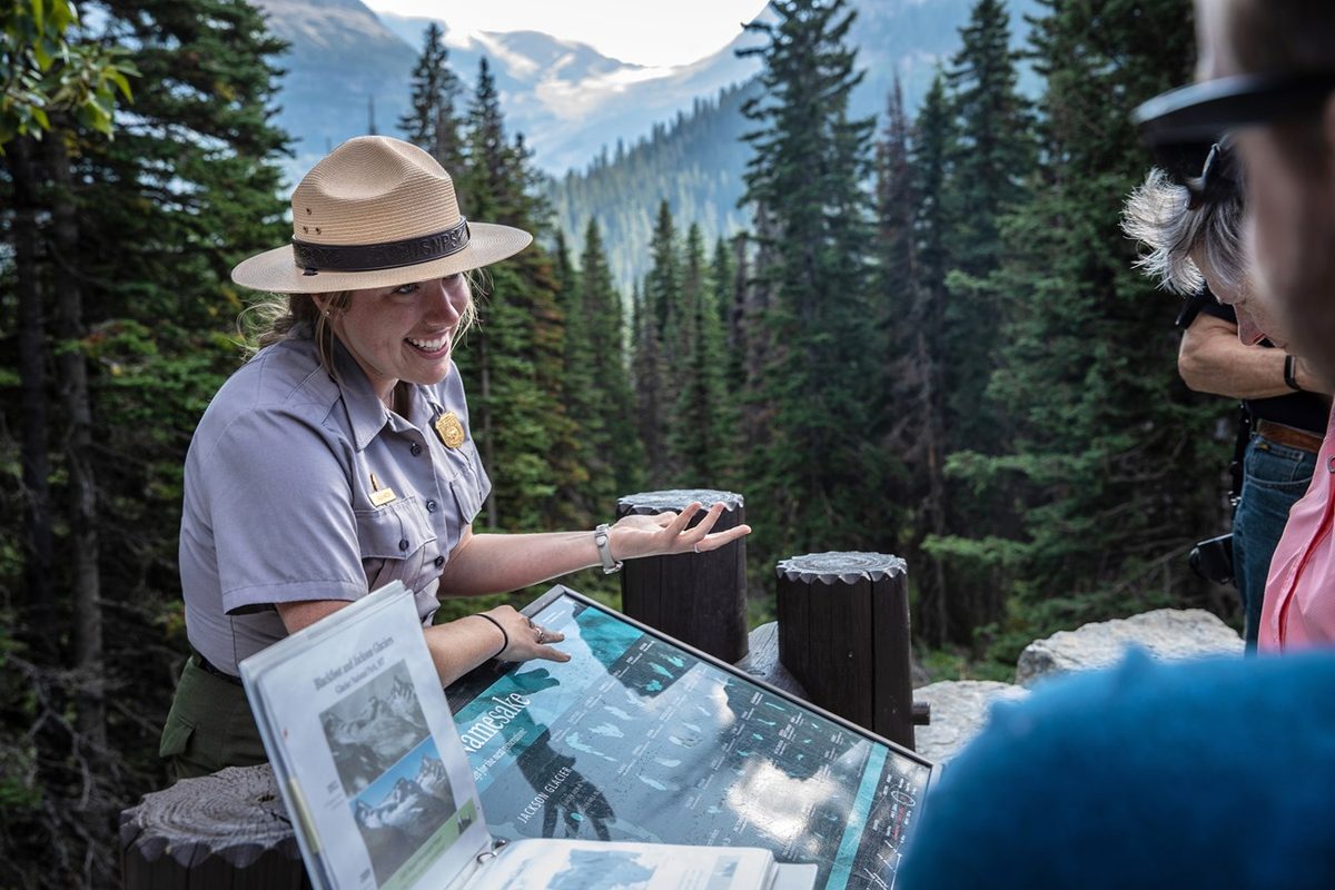 A park ranger showing a visitor a trail map, representing the ranger user narrative
